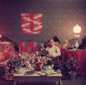 Author Truman Capote (1924 - 1984) relaxes with a book and a cigarette in his cluttered apartment, Brooklyn Heights, New York. Original Publication: A Wonderful Time - Slim Aarons (Photo by Slim Aarons/Getty Images)